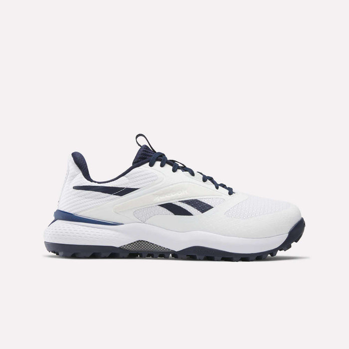The Reebok Nano Golf Shoes are white athletic sneakers with navy accents, navy laces, the Reebok logo on the side, a grip-textured sole, and a lightweight FlexWeave upper for breathability. Shown in side profile on a plain background.