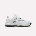 The Reebok Nano Golf Shoes are white with black and gray accents, a lightweight FlexWeave upper, mesh details, and a textured rubber sole for traction. Shown in side profile against a plain light background.