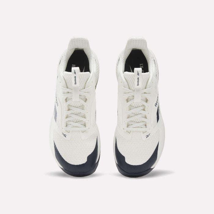 A pair of Reebok Nano Golf Shoes in white and navy, viewed from above, showcasing the laces, tongue logo, and side branding against a plain light background—these sneakers draw inspiration from lightweight golf shoes and are equipped with Floatride foam for enhanced comfort.