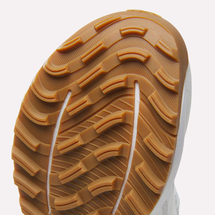 Close-up of the sole on Reebok Nano Golf Shoes, featuring a white upper and textured gum rubber outsole with deep, curved treads for traction—enhanced by lightweight FlexWeave for added durability.