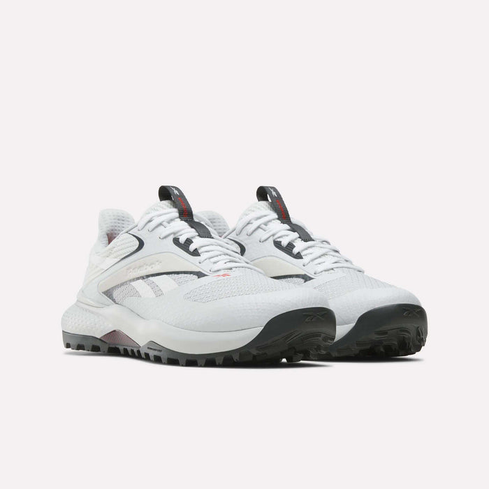 A pair of Reebok Nano Golf Shoes with a lightweight FlexWeave upper, thick textured soles, black and gray accents, and black pull tabs are placed side by side on a plain white background.