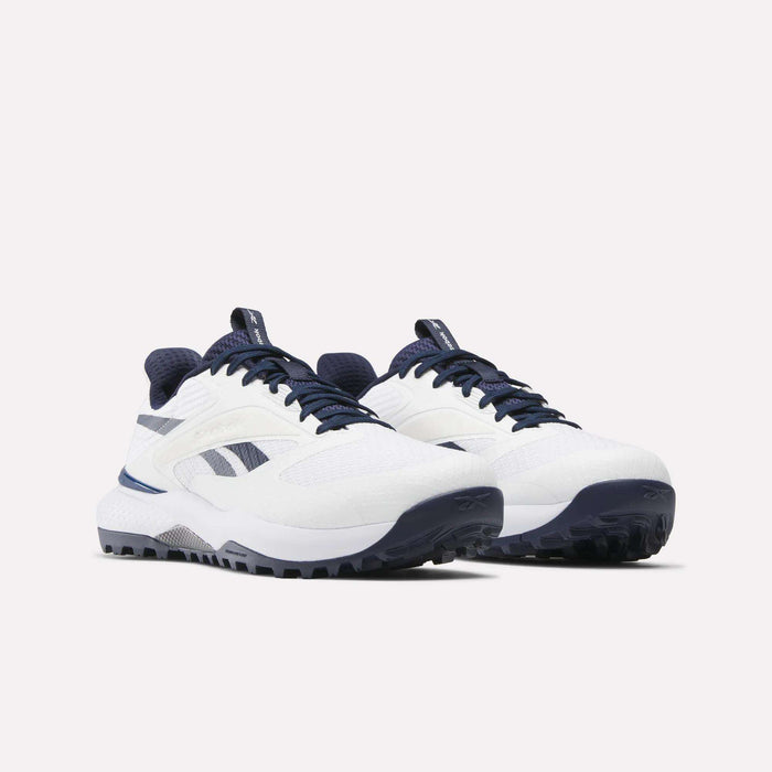 The Reebok Nano Golf Shoes are white athletic sneakers with navy blue accents, a lightweight FlexWeave upper, textured soles, and the Reebok logo on the sides. They are shown on a plain white background.