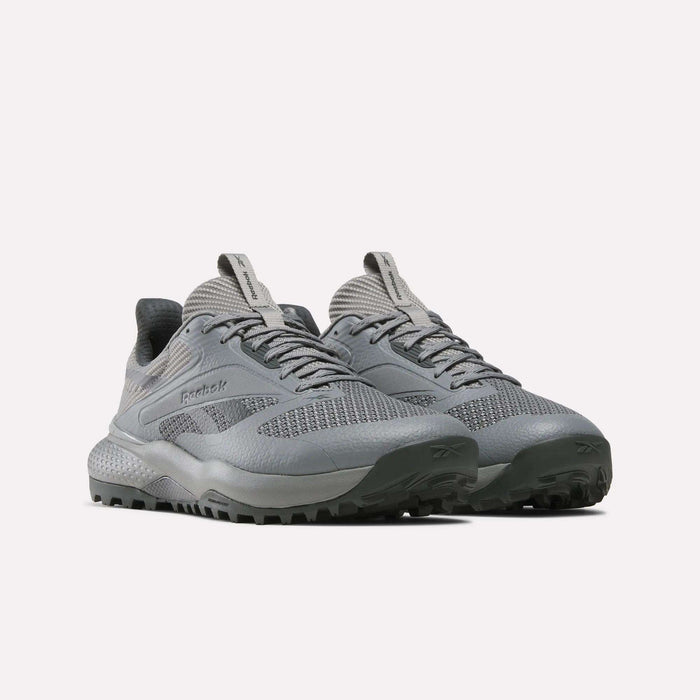 A pair of gray Reebok Nano Golf Shoes featuring textured soles, a lightweight FlexWeave upper, and tongue pull tabs, displayed against a plain white background.