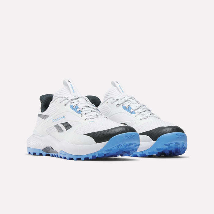 A pair of Reebok Nano Golf Shoes in white with black accents, light blue soles, a breathable FlexWeave upper, textured design, and side Reebok logo, shown on a white background.