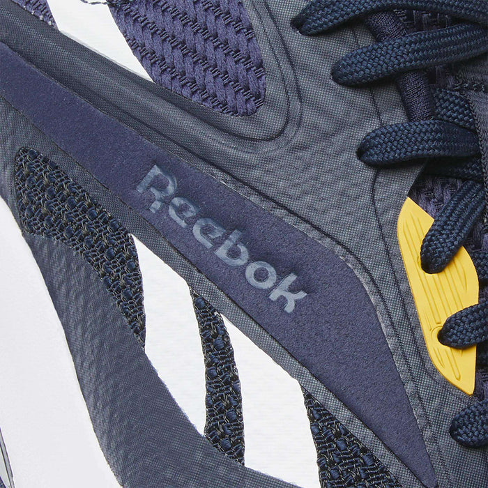 Close-up of Reebok Nano Golf Shoes in navy blue, featuring a lightweight FlexWeave upper, blue laces, yellow accents, and the Reebok logo on the side for comfort and style.