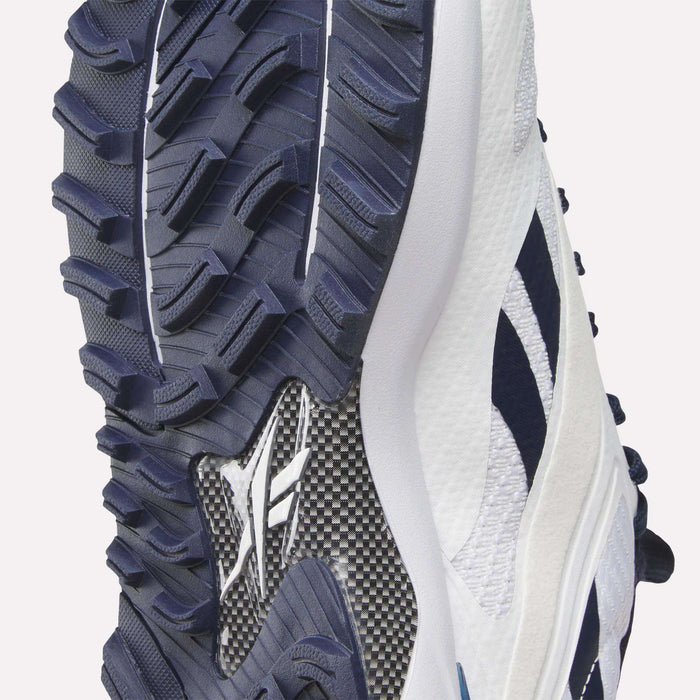 Close-up of the sole on Reebok Nano Golf Shoes, showing deep navy treads, a lightweight FlexWeave upper, and a carbon-fiber-style midsole—all highlighting the grip and build quality.
