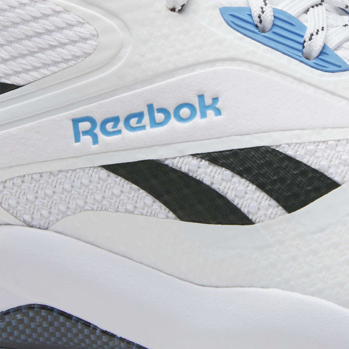 Close-up of Reebok Nano Golf Shoes in white, showing the blue Reebok logo, black stripes, durable FlexWeave upper, white textured mesh, and a blue shoelace eyelet.