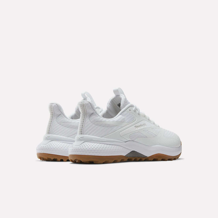 A pair of Reebok Nano Golf Shoes in white with textured details and tan rubber soles, made from lightweight FlexWeave, shown from a rear three-quarter angle on a plain white background.