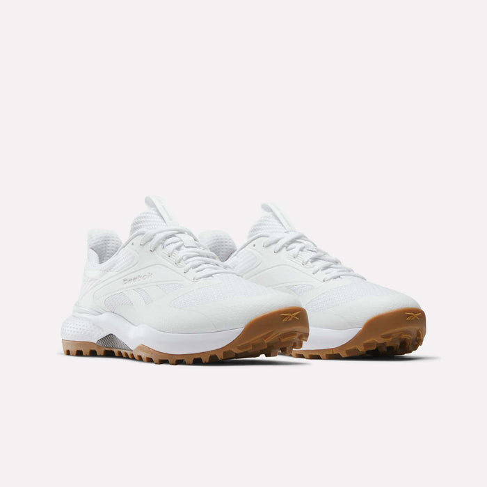 The Reebok Nano Golf Shoes are white athletic sneakers with lightweight FlexWeave uppers and gum rubber soles, shown angled on a plain white background. They feature textured details and Reebok branding on the side.