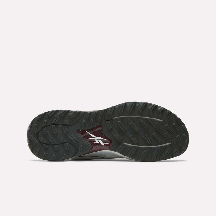The image shows the bottom view of Reebok Nano Golf Shoes, featuring a dark sole with a textured tread pattern and a white Reebok logo in the center, highlighting the performance-focused design.