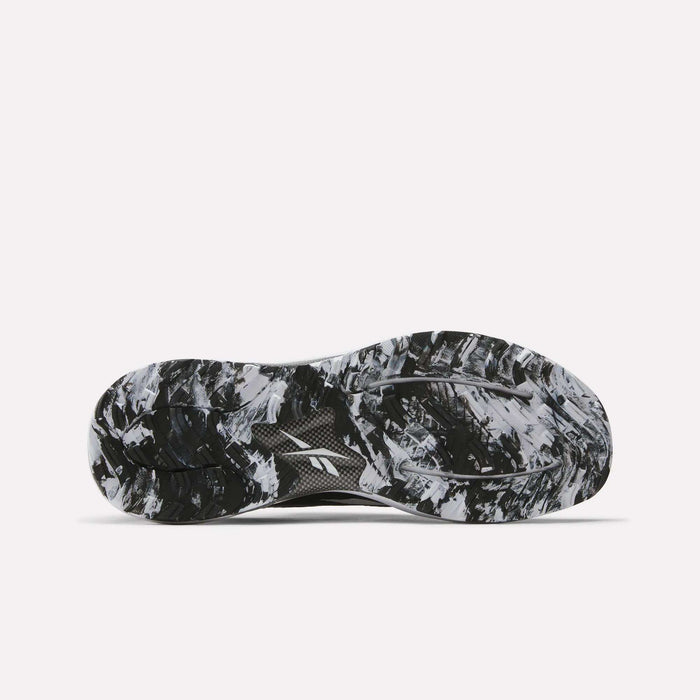 The image displays the black and white marbled sole of Reebok Nano Golf Shoes, viewed from below to showcase the grip pattern and tread design that complement performance foam for enhanced comfort.