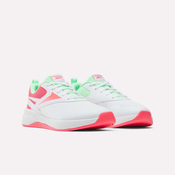 The Reebok Nano Play Shoes for little kids feature a white design with neon pink soles, pink accents, and green details on the tongue and heel, along with white laces. They're shown against a plain light background.