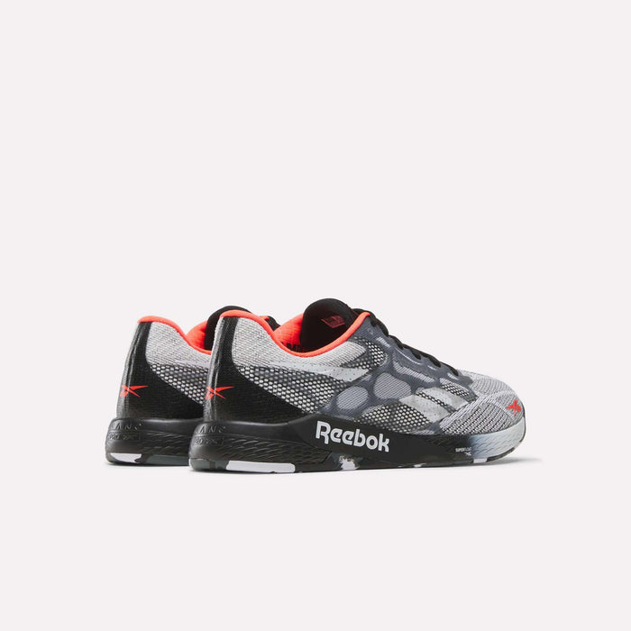 The Reebok Nano Pro Training Shoes are shown from back and side angles, featuring a black, gray, and white pattern with red accents and a black sole with the Reebok logo—ideal for competitive athletes.