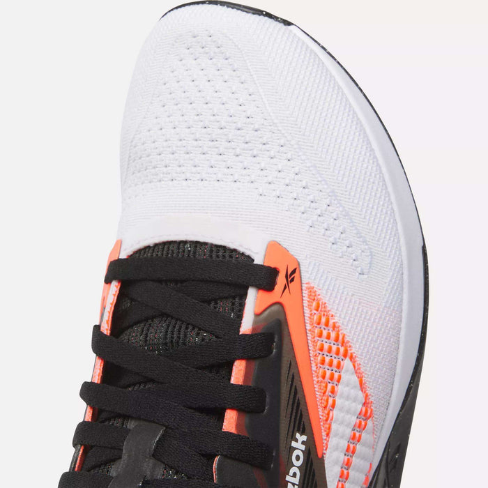 Close-up of the toe area of Reebok Nano X4 Training Shoes, featuring white mesh for breathability, black laces, orange and black accents, and a visible Reebok logo—perfect modern athletic footwear for training.