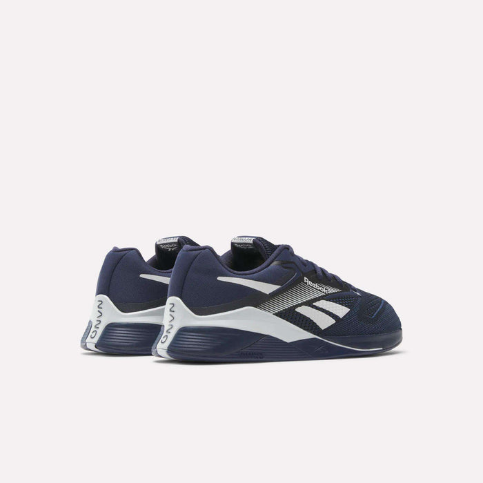 A pair of Reebok Nano X4 Training Shoes in navy blue with white and black accents, Flexweave mesh uppers, chunky white midsoles featuring navy and gray details, set against a plain light background.