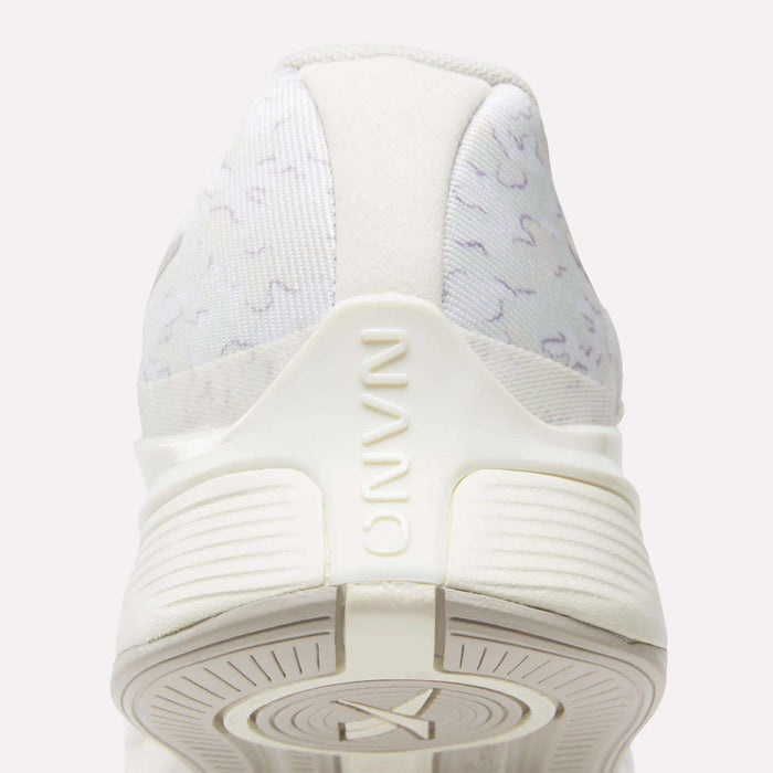 Close-up rear view of Reebok Nano X4 Training Shoes in white with subtle gray patterns, "NANO" embossed on the heel, and a textured sole. Lightweight, breathable features are visible at the bottom.