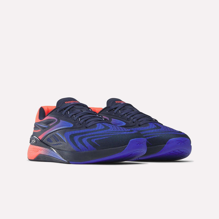 A pair of Reebok Nano X5 Edge Training Shoes with navy blue uppers, purple accents, and red-orange details on the tongue and heel, displayed against a plain white background.