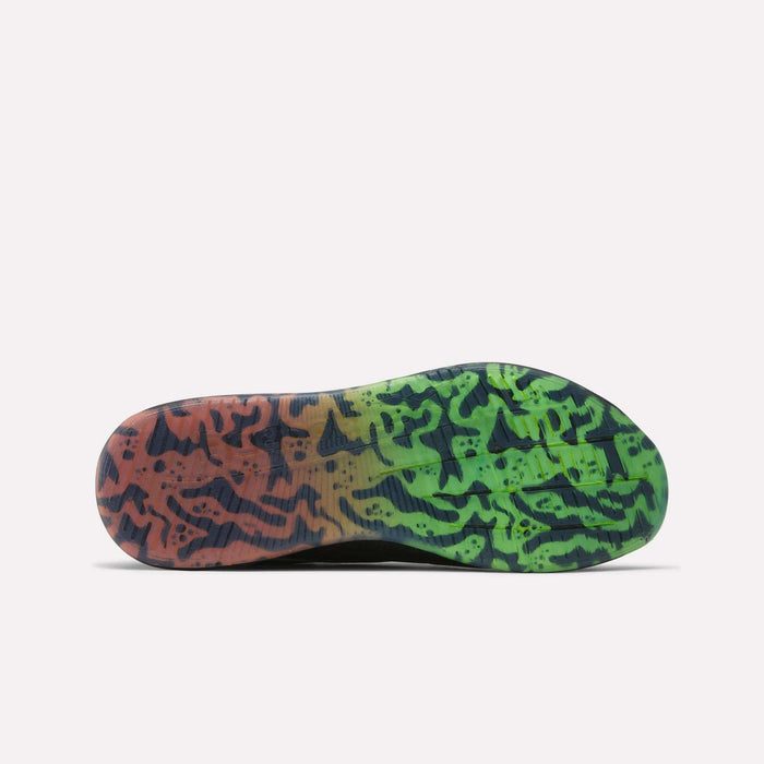 The image displays the sole of the Reebok Nano X5 Edge Training Shoe, showcasing a Flexweave design with a camouflage pattern that transitions from orange and red on the left to green and yellow on the right, accented by black tiger-like stripes.