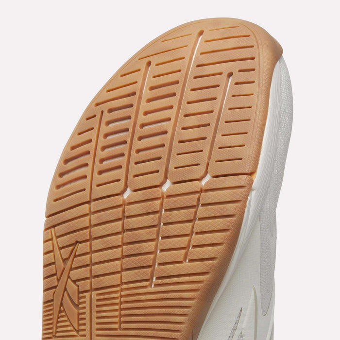 Close-up of the front of a white Reebok Nano X5 Edge Training Shoe, showing its textured light brown rubber outsole with grooves and patterns for improved traction and performance.