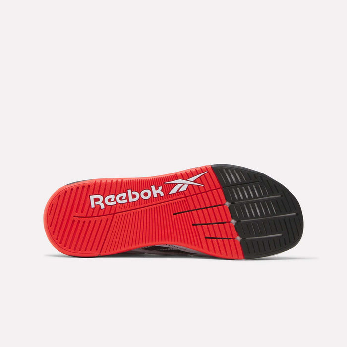 The image shows the sole of the Reebok Nano X5 Edge Training Shoes. The red sole features Flexweave material, a black toe area, and "Reebok" with the logo in white. Its tread includes multiple grooves for better grip.