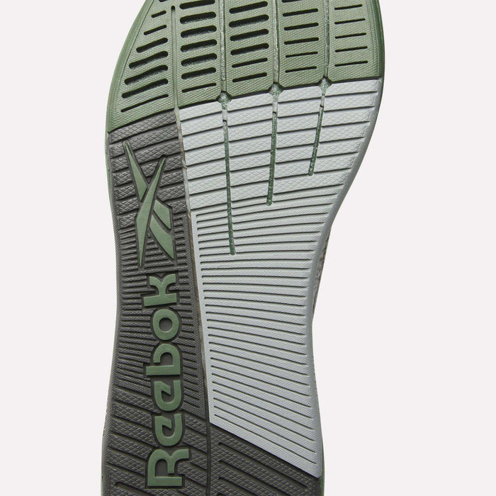 The image displays the sole of Reebok’s Nano X5 Training Shoes for men, boasting a mix of light green and gray, textured grip patterns, horizontal grooves, and the signature Reebok logo—ideal for stylish comfort during training.