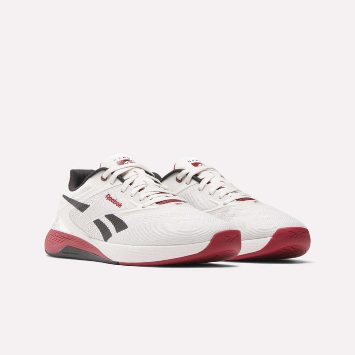 A pair of Reebok Nano X5 Training Shoes for men in white with black and red accents, including black side logos, black heel tabs, and red soles, displayed side by side on a white background.