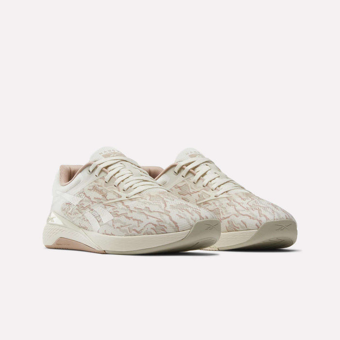 The Reebok Nano X5 men's training shoes feature a beige, patterned textured upper with light brown accents, displayed against a plain white background.