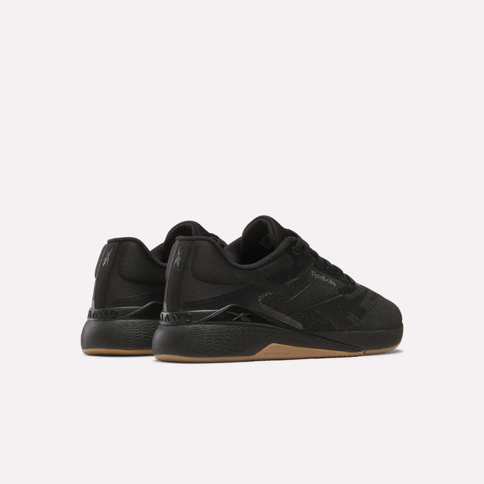 A pair of Reebok Nano X5 Training Shoes in black with mesh uppers, gum soles, and subtle branding, displayed from a rear-side angle on a plain white background.
