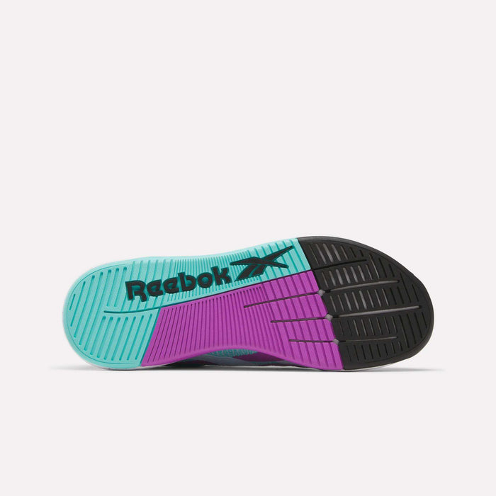 The image shows the sole of the Reebok Nano X5 Training Shoe, featuring three color sections—aqua blue on the left, purple in the middle, and black on the right—with "Reebok" and its logo printed in black on the blue section.