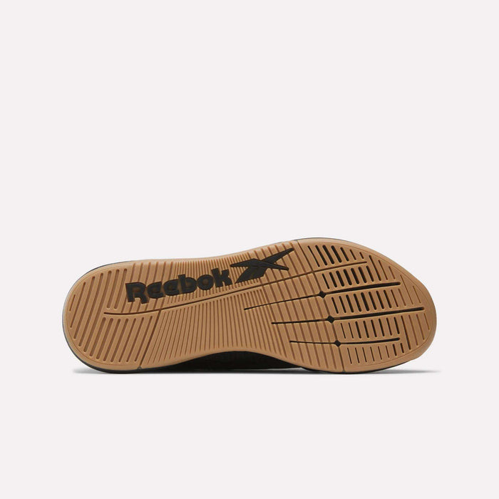 The image shows the sole of a Reebok Nano X5 Training Shoe featuring tan rubber with a detailed tread pattern and the black Reebok logo and vector design at the center.