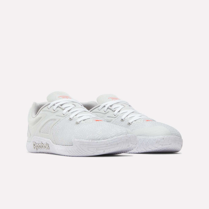 A pair of Reebok Nano Zero Training Shoes in white with subtle pink accents, textured mesh uppers, laces, and cushioned soles is displayed against a plain white background.