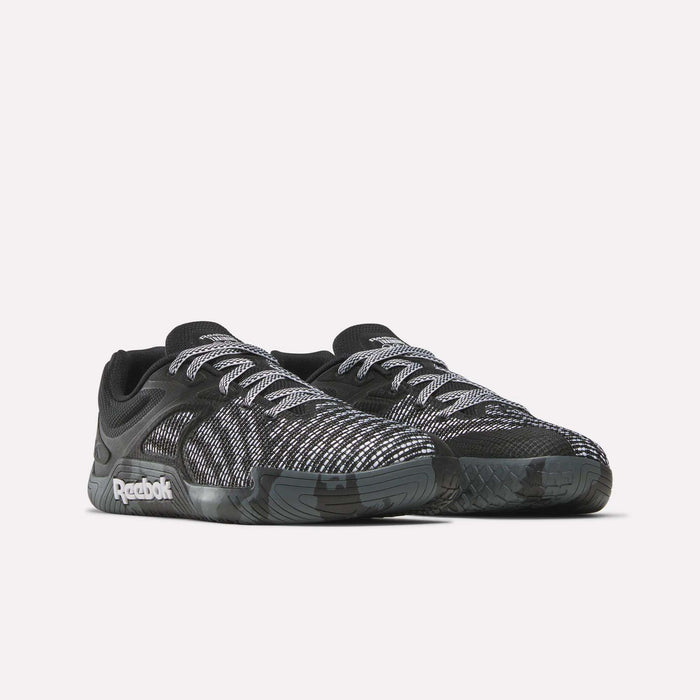 The Reebok Nano Zero Training Shoes feature black uppers with white and gray patterns, white laces, and a black sole—ideal for strength training. Shown on a plain white background.