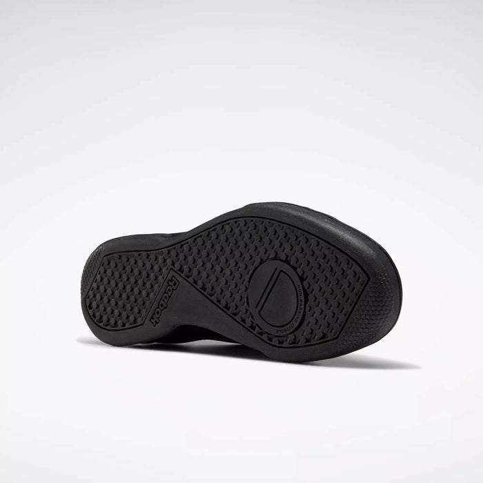 The image shows the sole of a black leather Reebok Men's NPC II Shoe on a plain light background, featuring a textured grip and embossed Reebok logo that showcase its retro court-inspired design—an iconic men's fashion sneaker.