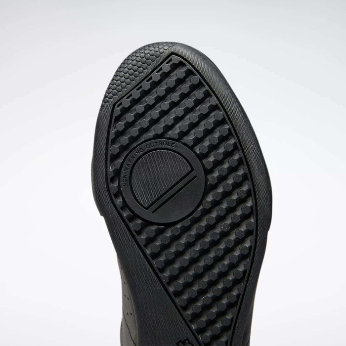 Close-up of the black rubber sole on Reebok Men's NPC II Shoes, featuring a textured geometric tread pattern and “NON-MARKING OUTSOLE” embossed in a circular design—highlighting retro court style.