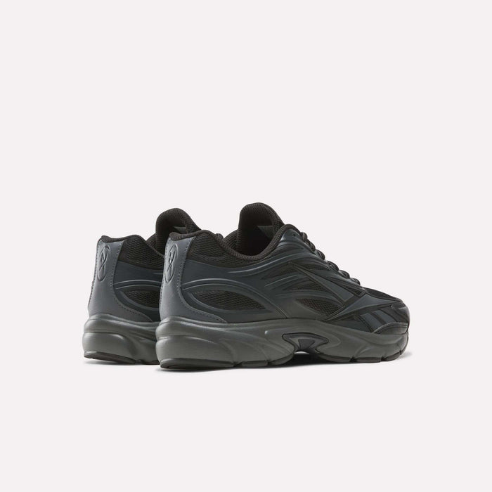A pair of Reebok Premier Road 1000 Shoes in black, featuring a chunky sole and distinctive wavy side details, are displayed on a white background at an angle that highlights the outer side and back—these retro-inspired Y2K sneakers blend nostalgic style with modern comfort.