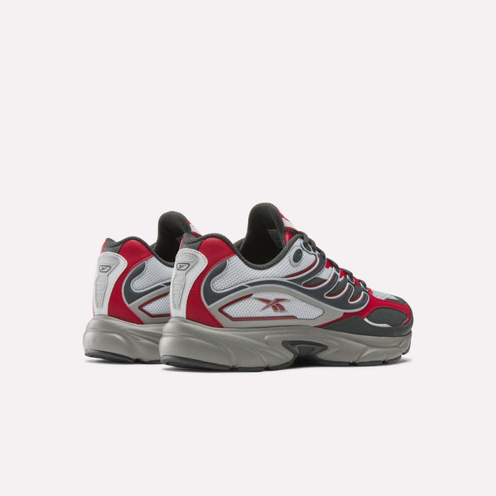 The Reebok Premier Road Control Shoes, featuring gray, black, white, and red accents, are displayed at an angle on a plain white background with the heels slightly facing the camera.