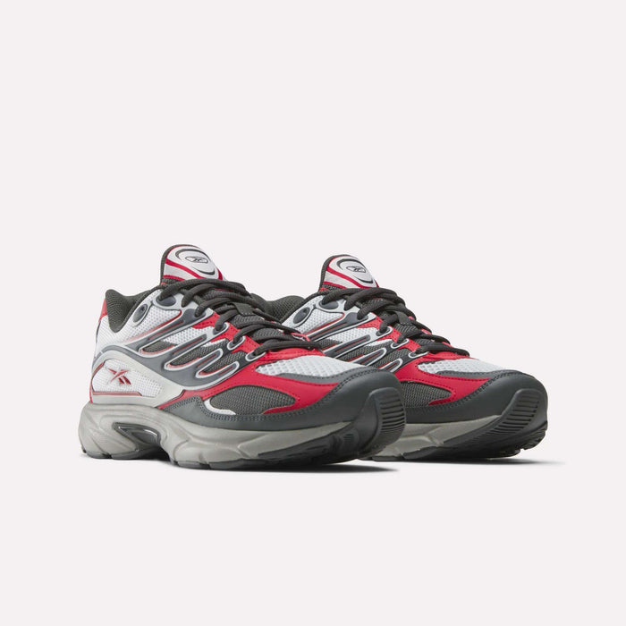 The Reebok Premier Road Control Shoes feature a gray, white, and red mesh upper, black laces, and thick textured soles. These cushioned sneakers give a sporty, modern edge to classic retro running shoe design.