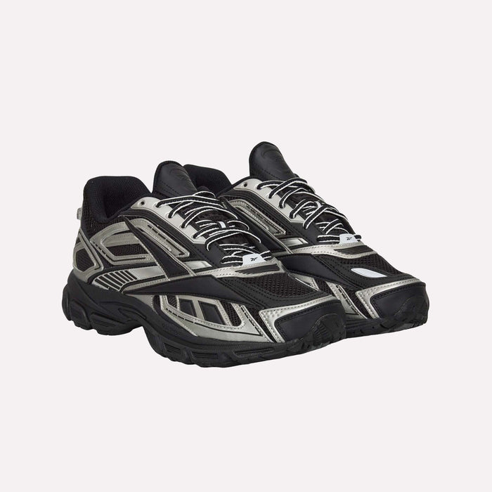 A pair of Reebok Premier Road Ultra Shoes in black and silver, featuring mesh and synthetic overlays, thick soles with a dual-density midsole, and white laces, are displayed against a plain light background.