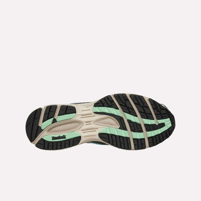 The image shows the bottom sole of the Reebok Premier Road Ultra Shoes, featuring black, beige, and mint green tread patterns that reference its archival running sneaker heritage, with the Reebok logo displayed on the left side.