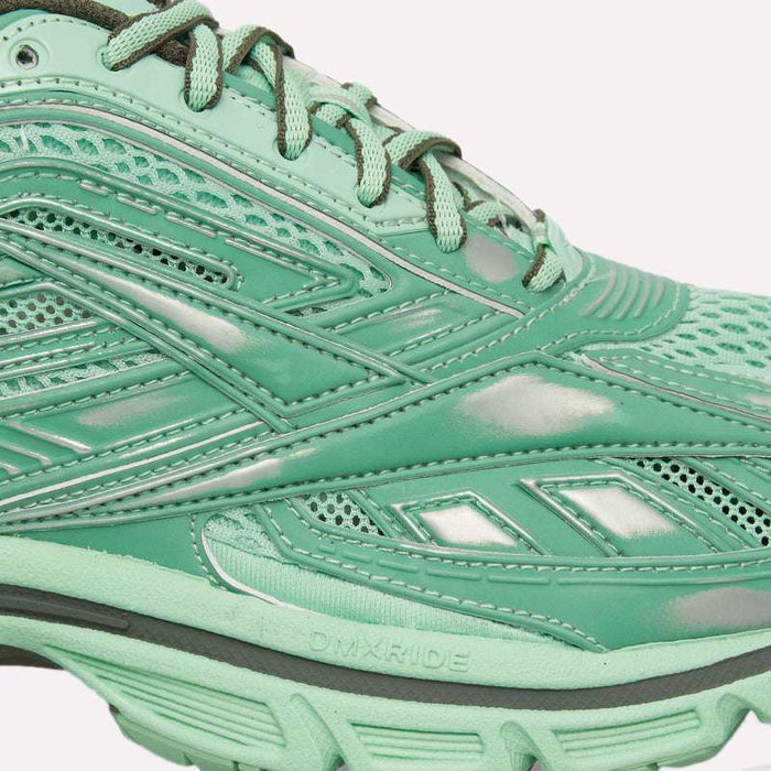Close-up of the Reebok Premier Road Ultra Shoes in mint green, showcasing their archival running silhouette with mesh and glossy synthetic overlays, detailed stitching, “DMX RIDE” text on the sole, and a dual-density midsole for enhanced comfort.