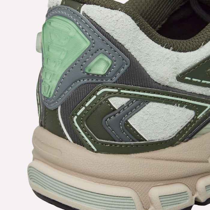 A close-up of the heel of the Reebok Premier Road Ultra Shoes highlights a mix of green, gray, white, and cream materials in a textured, layered design inspired by classic Reebok running silhouettes. The dual-density midsole delivers enhanced comfort and style.