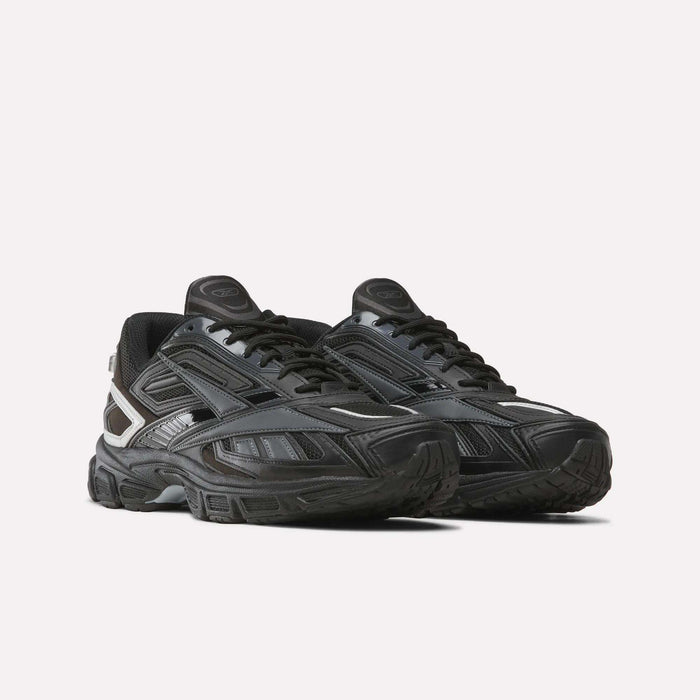 The Reebok Premier Road Ultra SV Shoes, featuring a black colorway with silver accents, thick soles, and a low-top silhouette reminiscent of classic 2000s running shoes, are displayed against a plain white background.