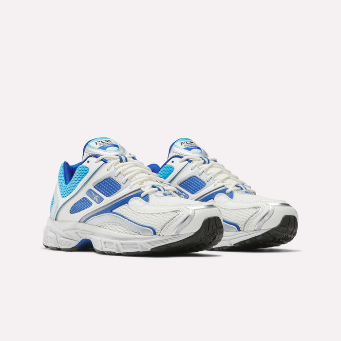 A pair of Reebok Premier Trinity Shoes in white with blue mesh accents, grey details, and black soles. These retro tech running shoes are shown on a plain white background.