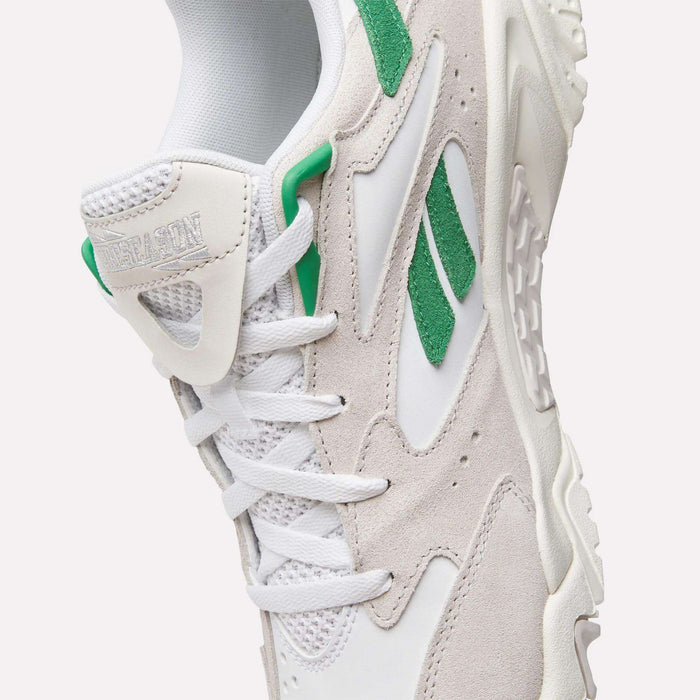 A close-up of the Reebok Preseason 94 Low Retro Basketball Shoes, featuring white and light gray tones, green suede accents, white laces, textured sole, and visible Reebok logos—blending '90s archive style with modern training performance.