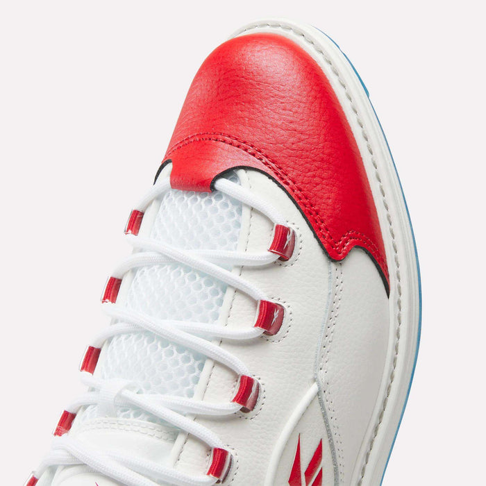 Close-up of Reebok Question Golf Shoes, featuring white leather with red accents on the toe and lace loops, white laces, mesh tongue, spikeless design, visible stitching, and a subtle side logo.