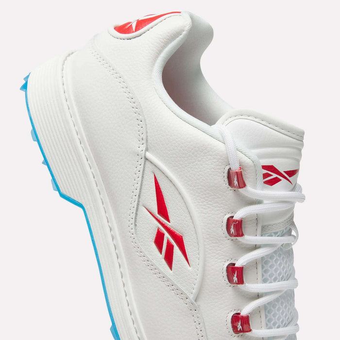 Close-up of Reebok Question Golf Shoes in white leather with red logos, red lace eyelets, and light blue spikeless outsole. Features white laces and textured panels for a sporty, modern style.
