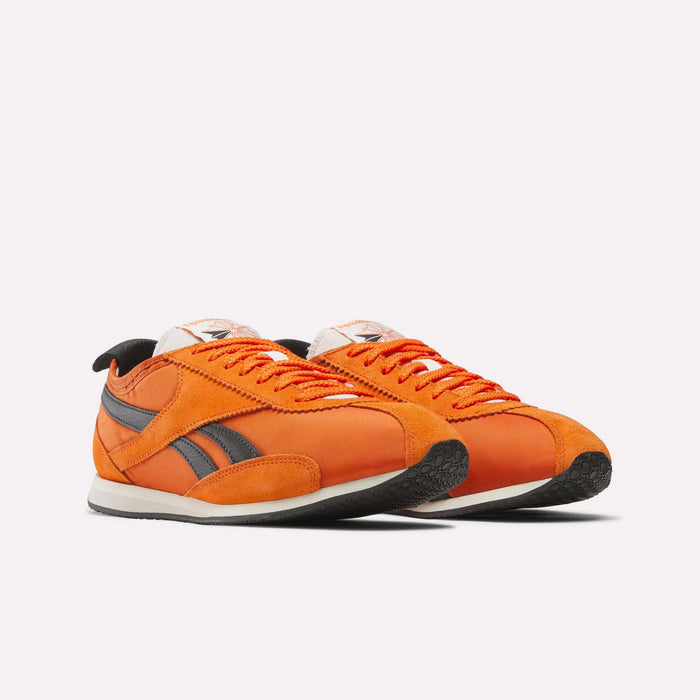 A pair of orange Reebok R400 Shoes with black detailing, white midsoles, and black outsoles are positioned side by side against a plain white background.