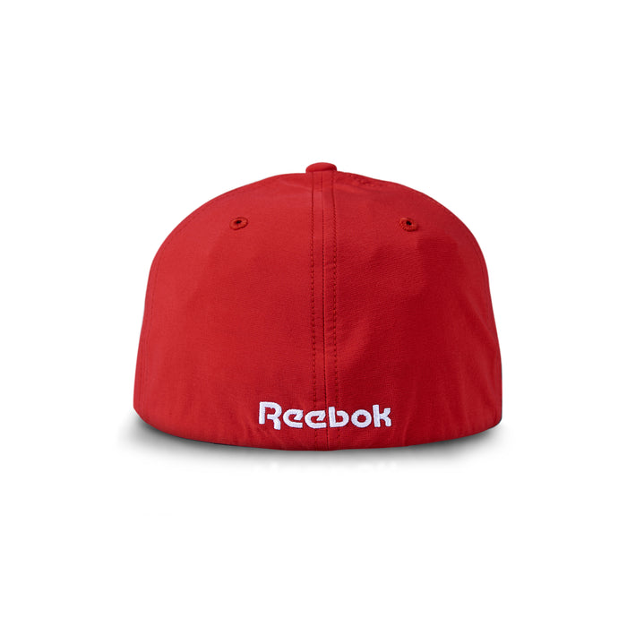 The Reebok Range Cap is a red golf hat with "Reebok" embroidered in white on the back. It features visible stitching, moisture-wicking fabric, sun protection, and two top ventilation holes.
