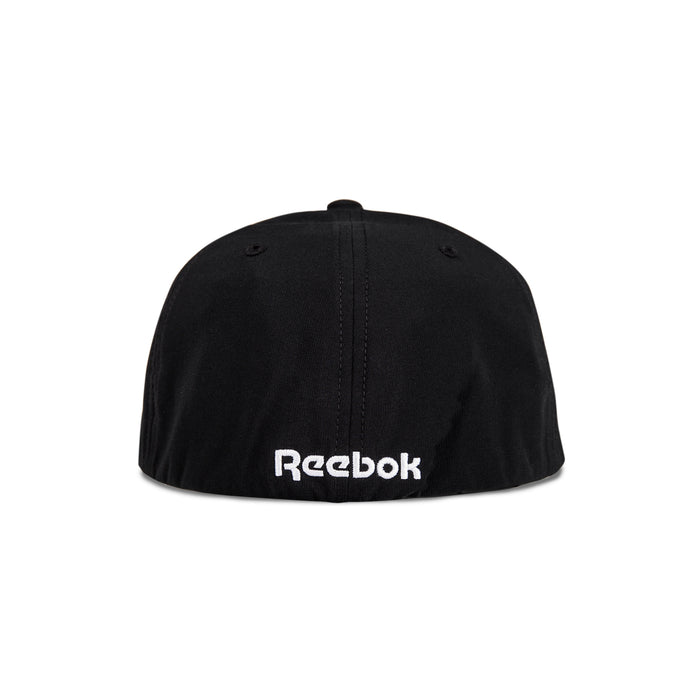 The image shows the back view of the Reebok Range Cap, a black cap featuring the white embroidered Reebok logo near the bottom edge.