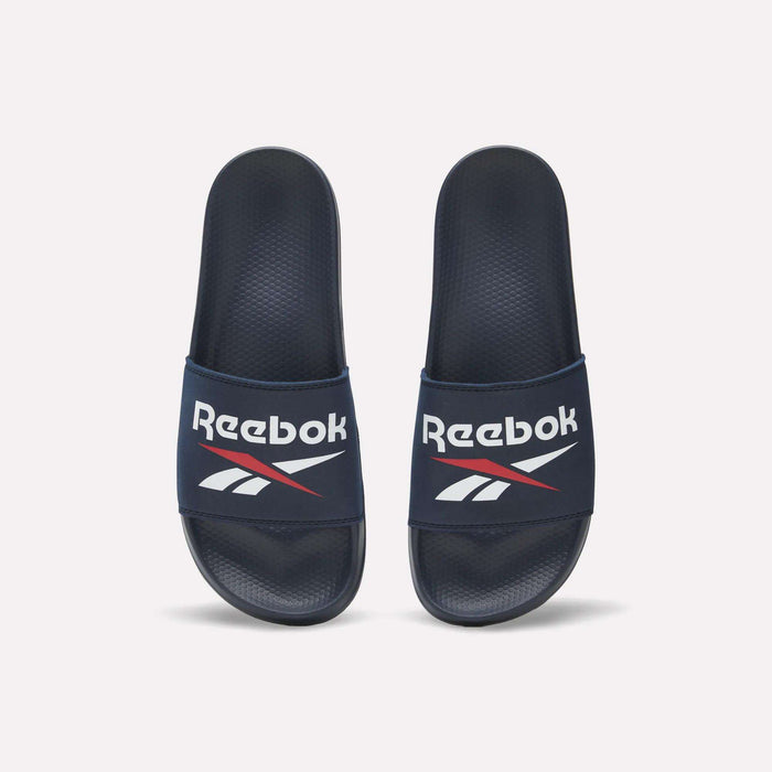 The Reebok RBK Fulgere Swim Slides in navy blue feature a white Reebok logo and red-accented top straps, shown side by side on a white background. Enjoy easy slip-on comfort for poolside or casual wear.
